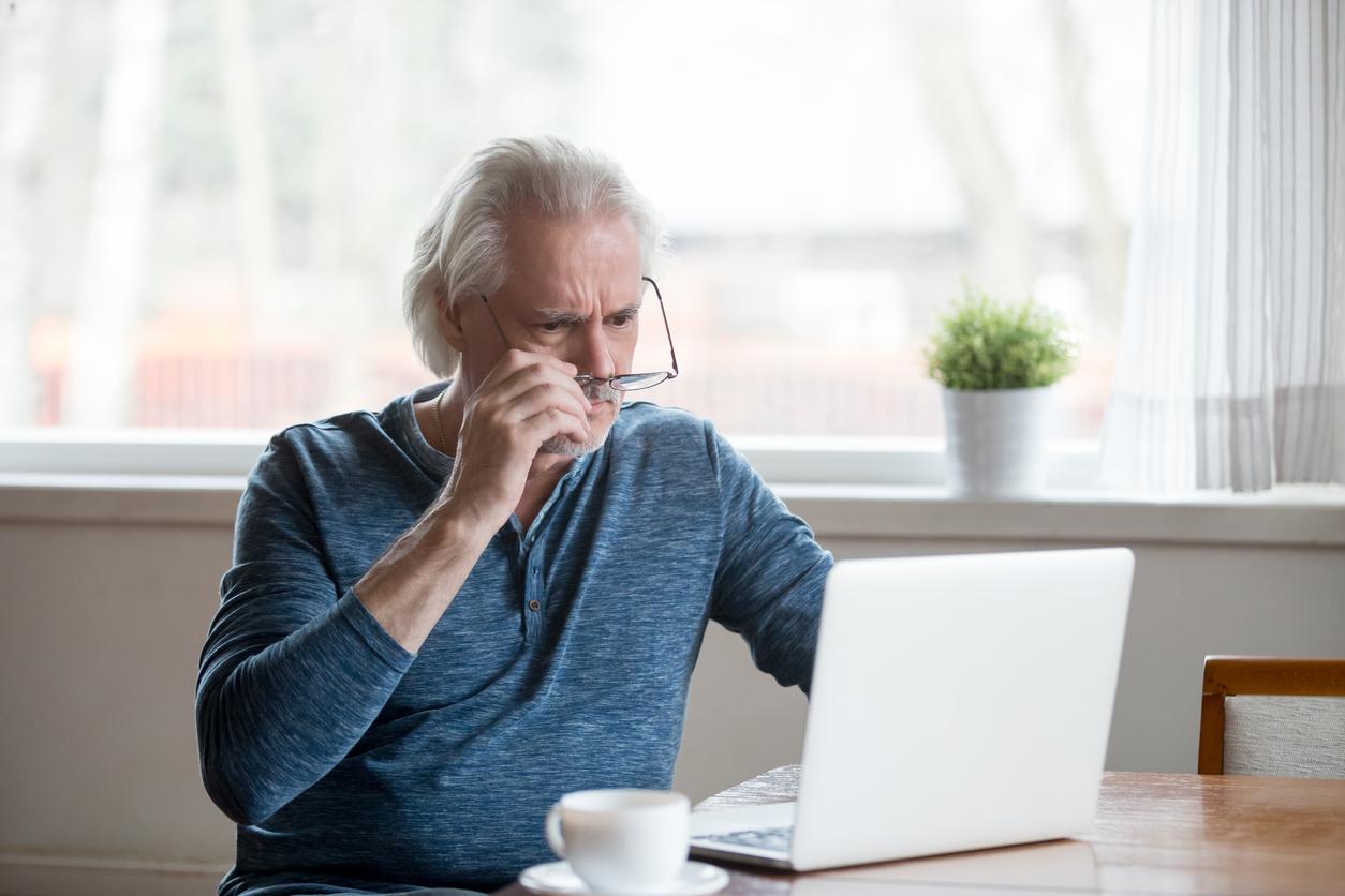 Elderly man looks at laptop