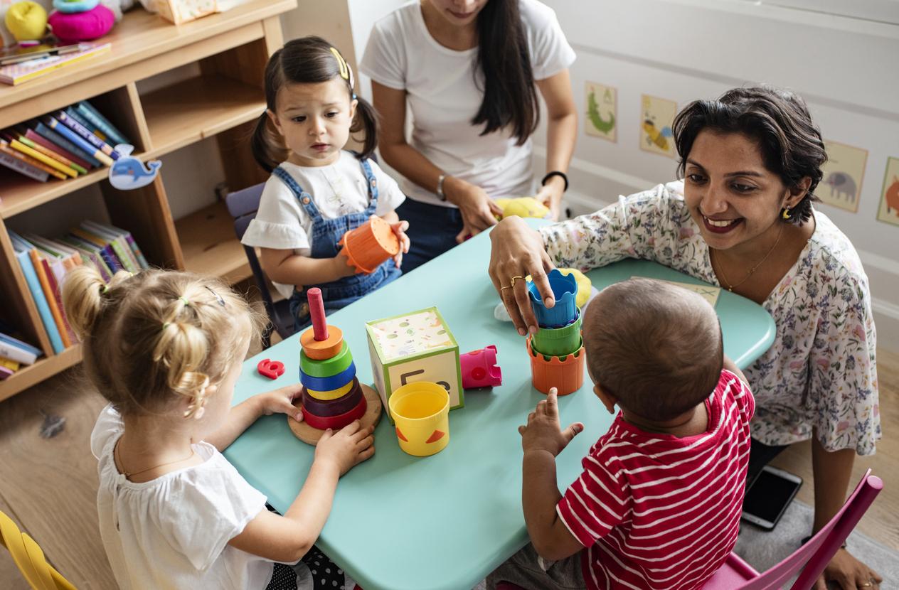 Female teacher plays with kids at table