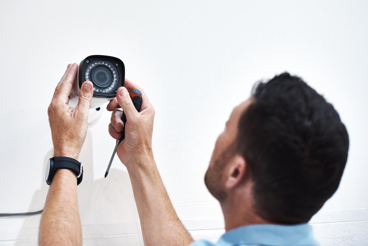 Shot of a mature man installing a security camera on a building