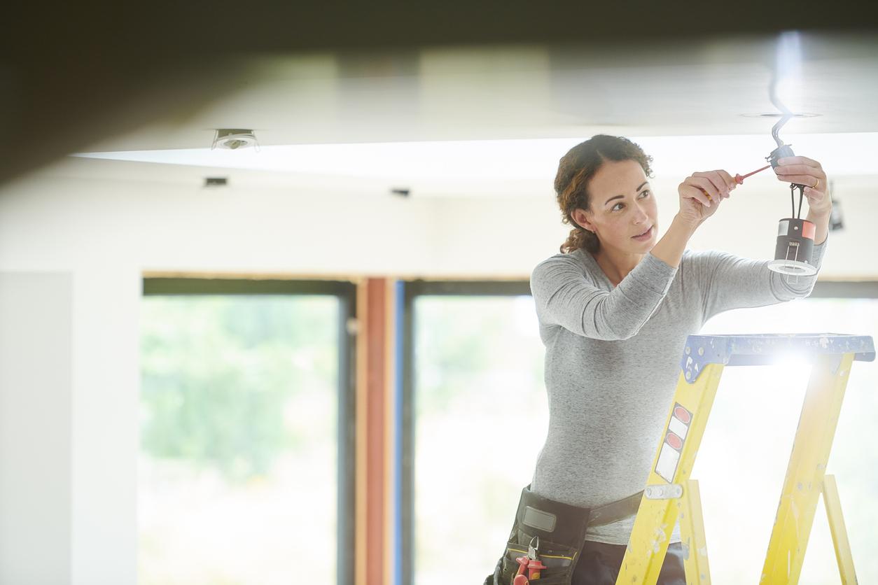 Female electrician installing downlights