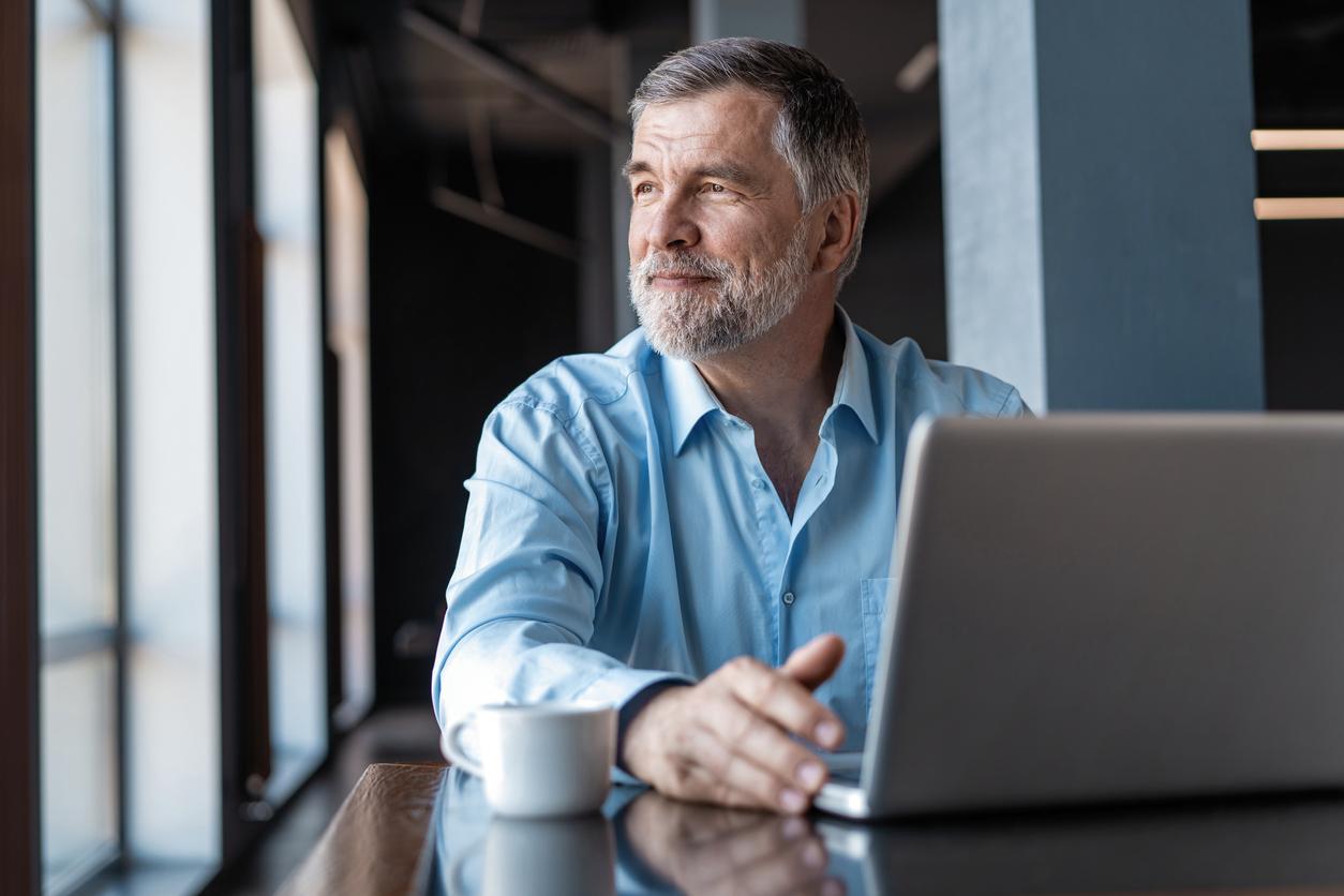 Man with laptop computer gazing out of a window