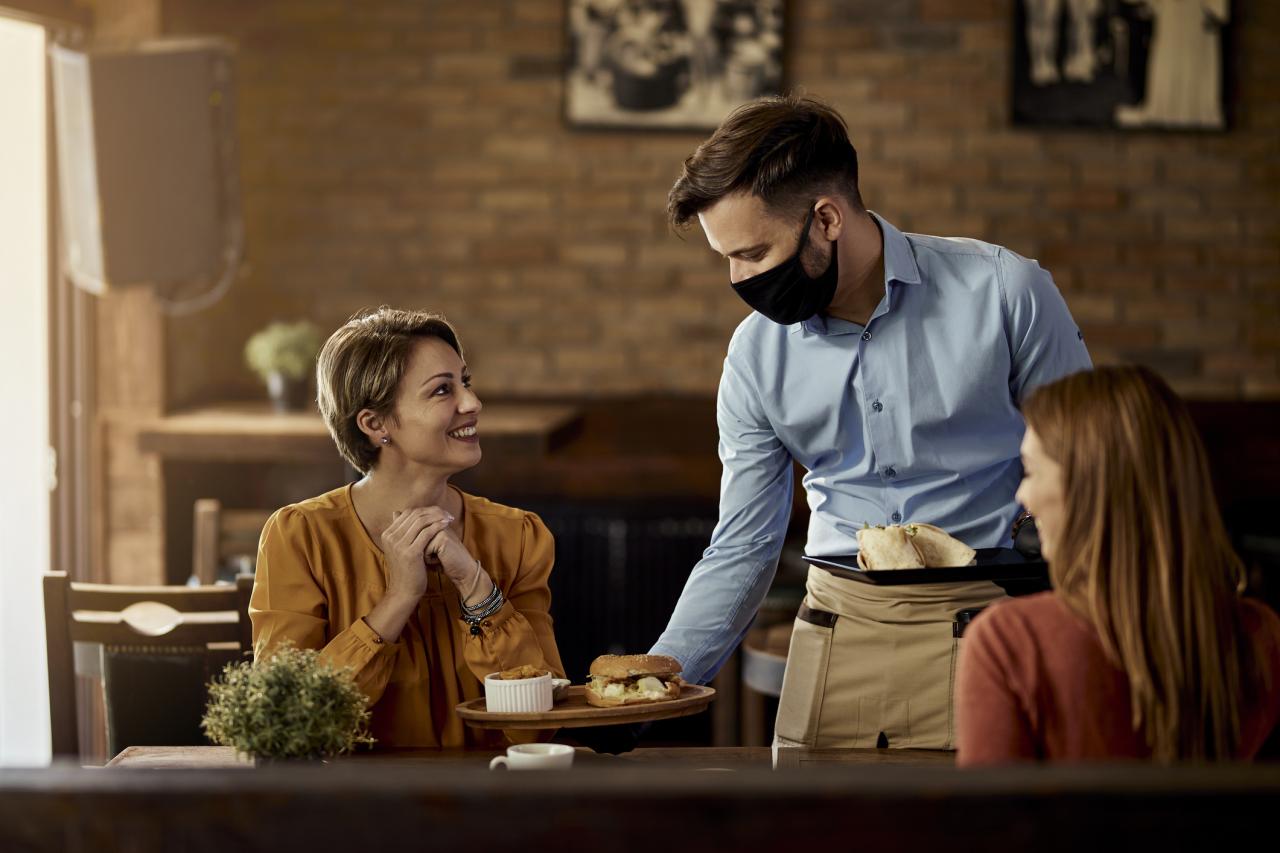 Man serving food to patrons in restaurant