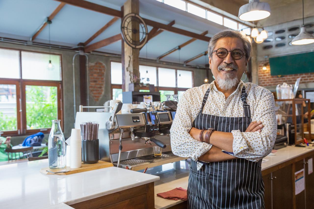 Smiling cafe owner in front of espresso machine