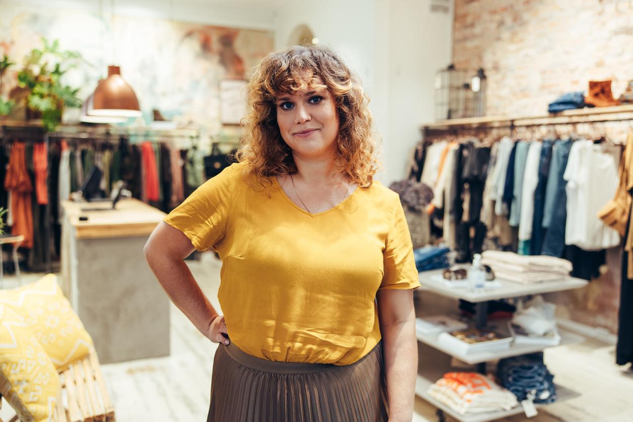 Owner of clothing shop standing in store