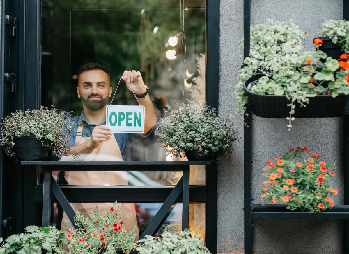 Male florist holding up "open" sign