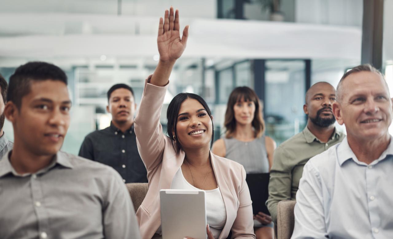 Woman raising her hand to ask a question at seminar