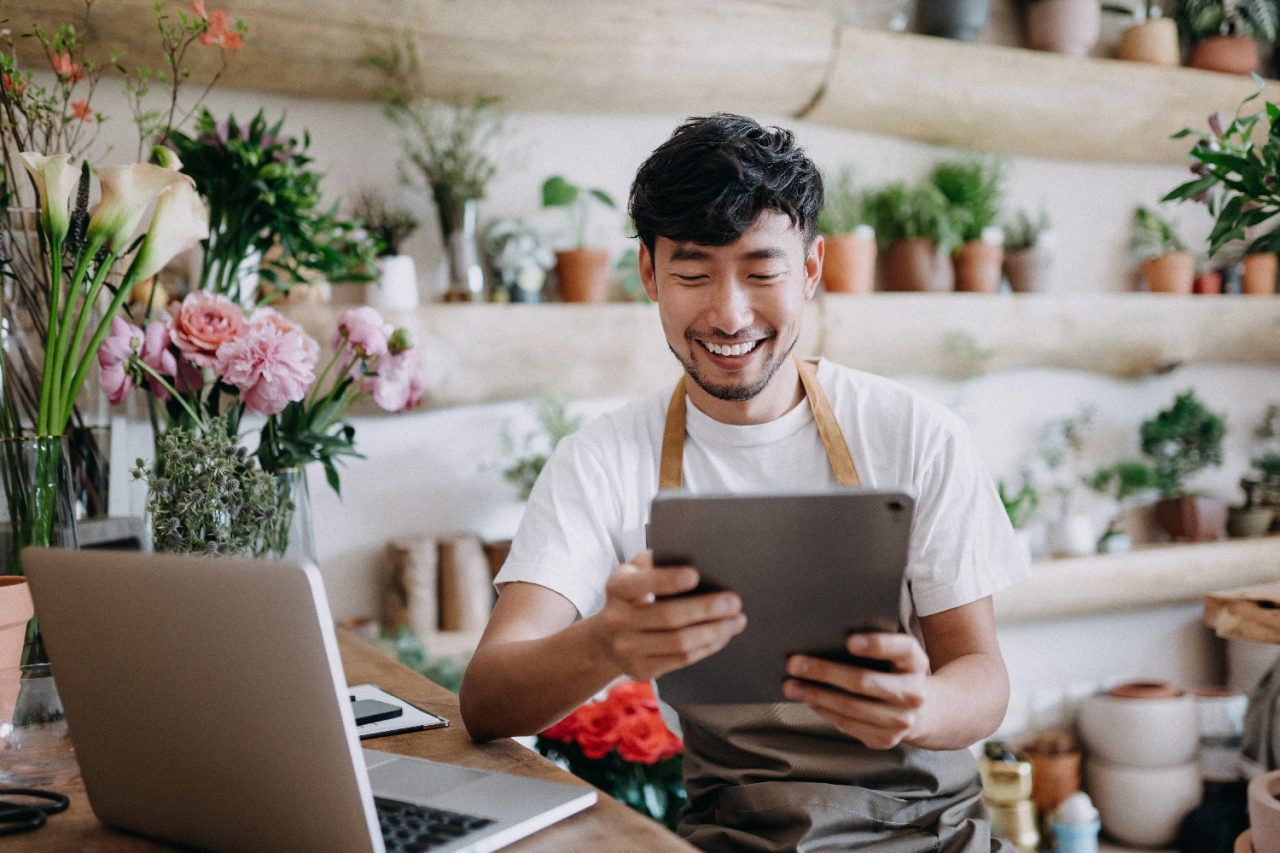 Male florist smiling at tablet