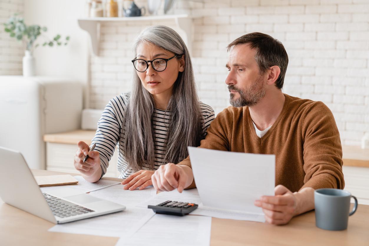 Man and woman look at laptop with documents