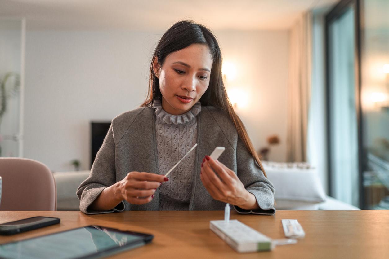 Asian woman looks at covid test