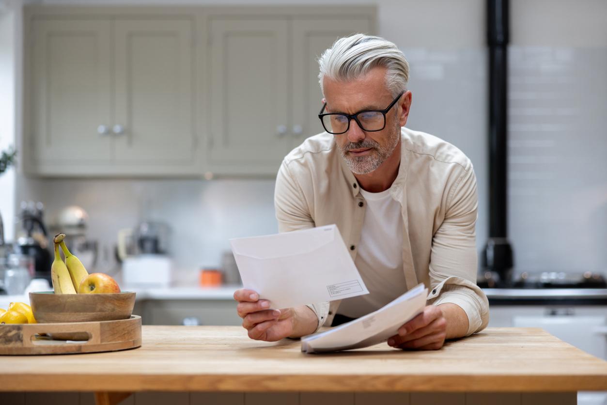 Man at home reading a letter in his mail stock photo