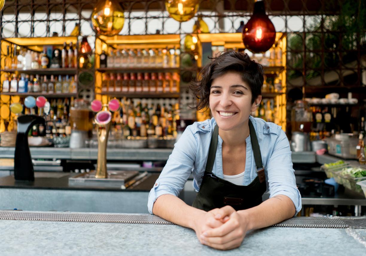 Woman leaning on bar in front of drinks display