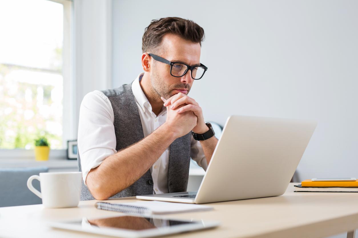 Man in glasses working on laptop from home stock photo