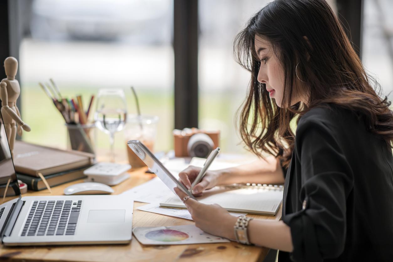 Woman sits at desk looking at laptop