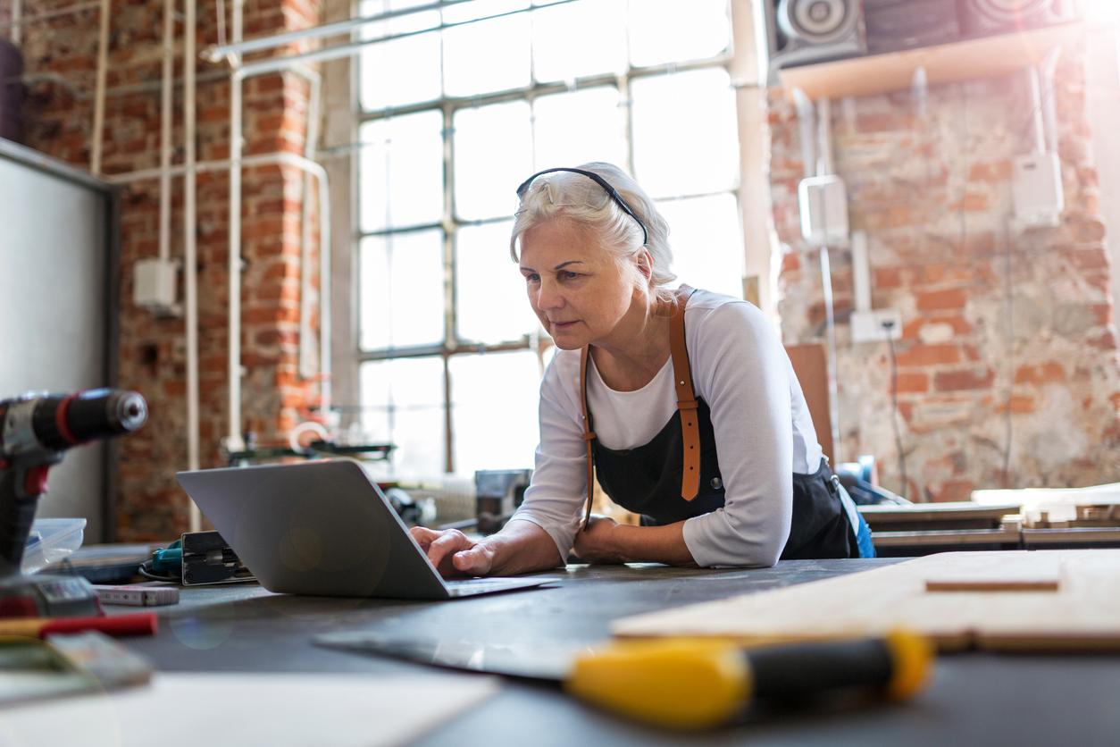 Senior woman using a laptop in a workshop